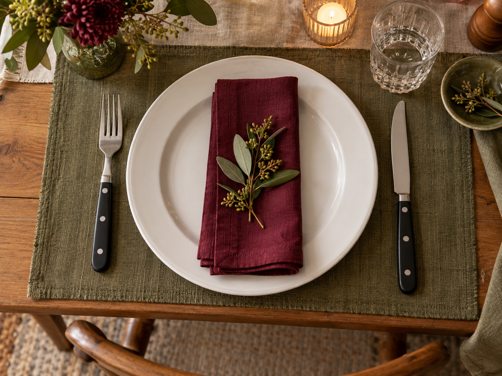 White plate with a burgundy napkin, black-handled cutlery and an olive placemat